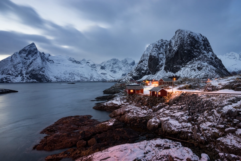 red cabins in front of snow covered mountains in Lofoten Islands