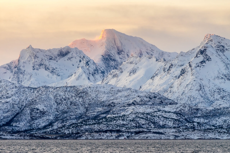 Winter sunrise, snow covered mountains with alpine glow.