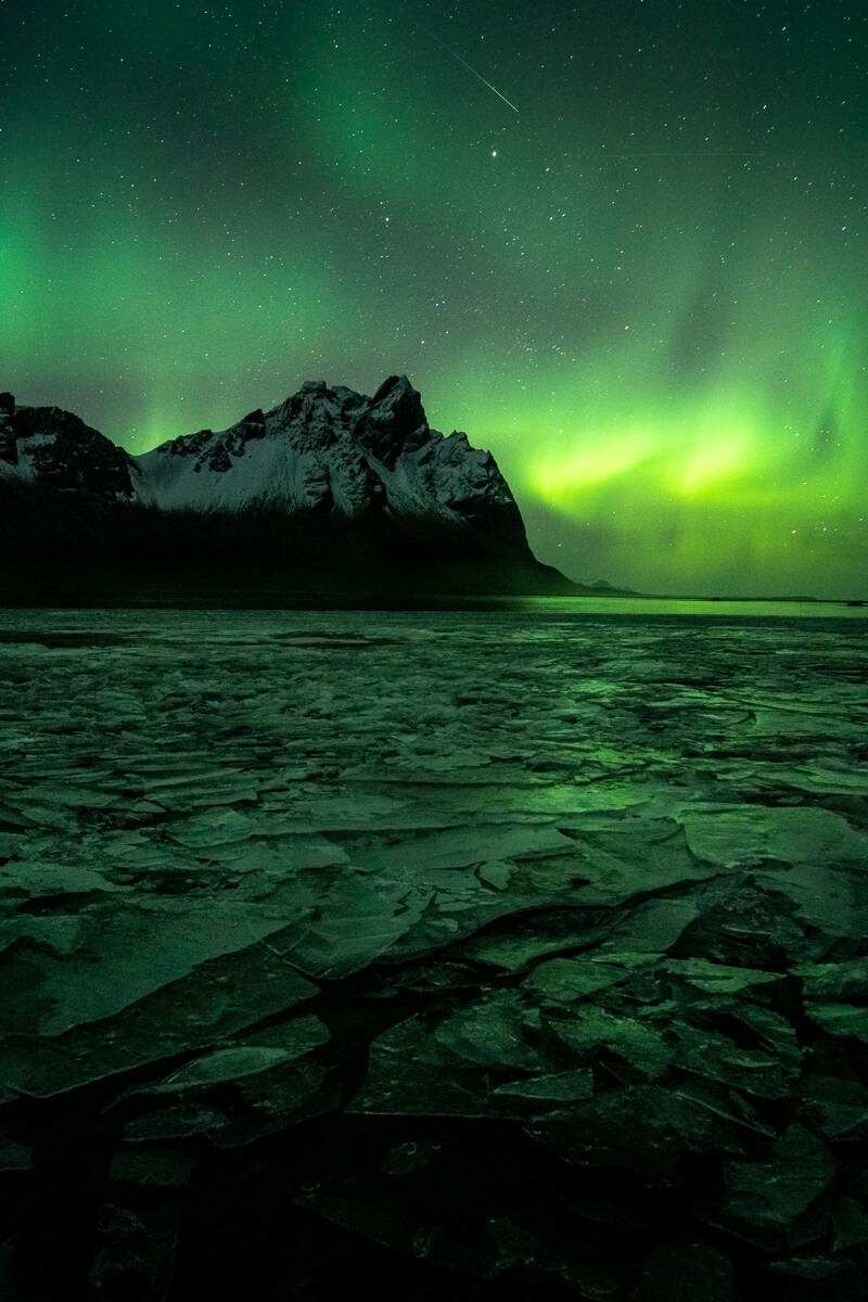Aurora Borealis over vestrahorn mountain reflecting of broken sheet ice