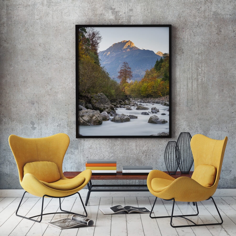 Autumn coloured trees along river with mountain in the distance.